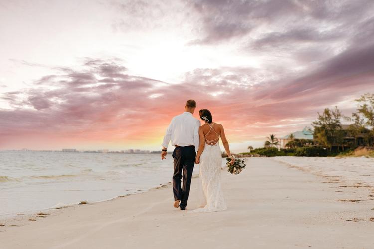 Wedding couple walking on beach during sunset
