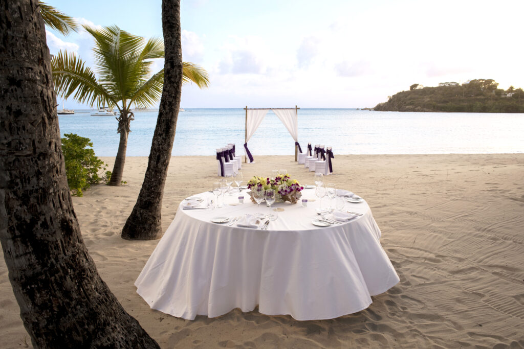 Wedding Setting by the Beach at Sunset in Caribbean with set Table, Palms and Sandy Beach
